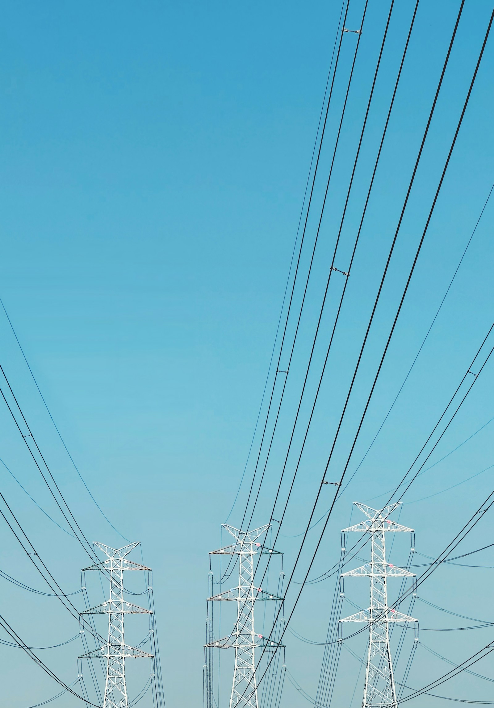 Electricity transmission towers and power lines beneath a blue sky
