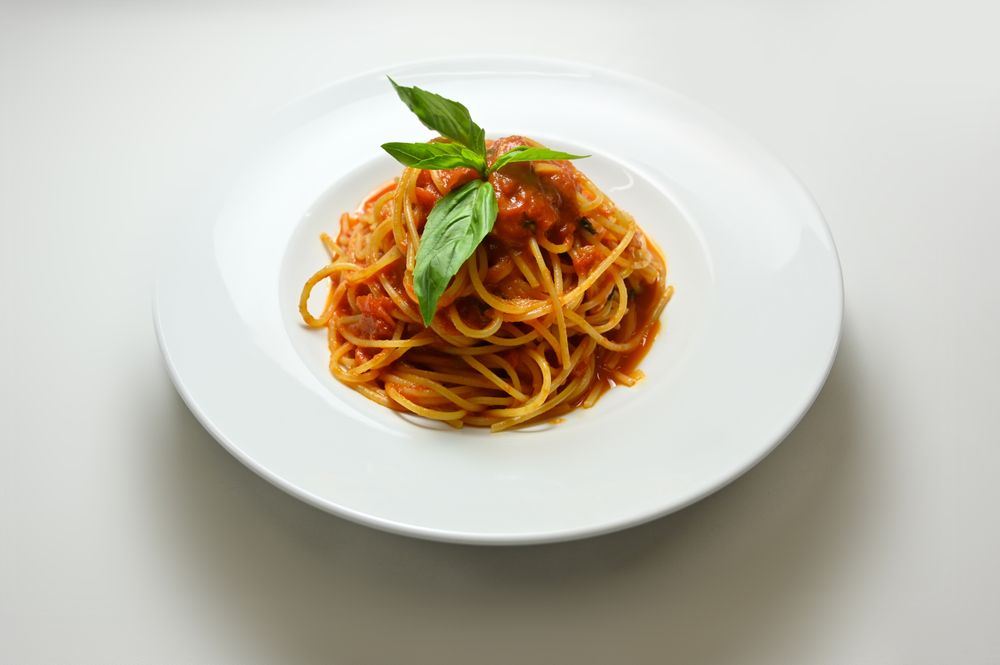 Spaghetti with tomato sauce and fresh basil on a white plate, featured in the Casa Lunara demo